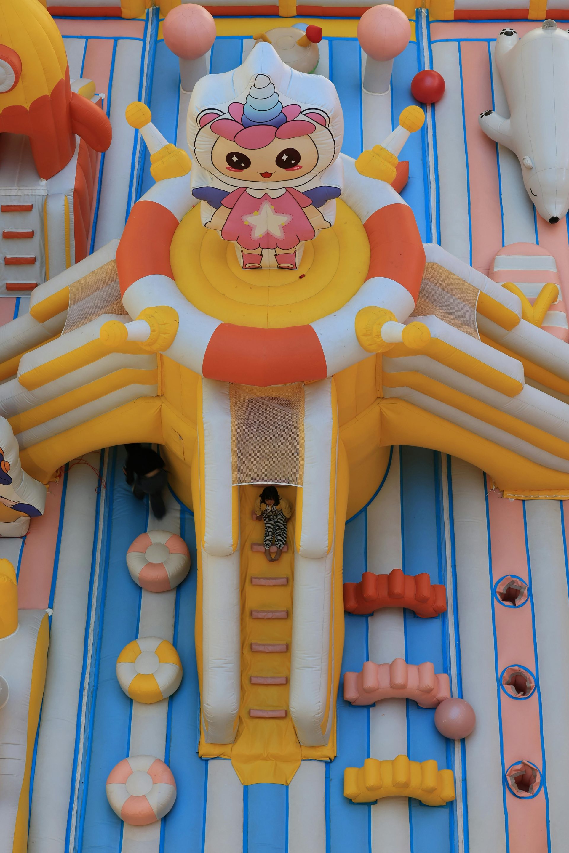 Draufsicht auf einen farbenfrohen, aufblasbaren Spielplatz mit Comic-Motiven, ideal für Kinder.