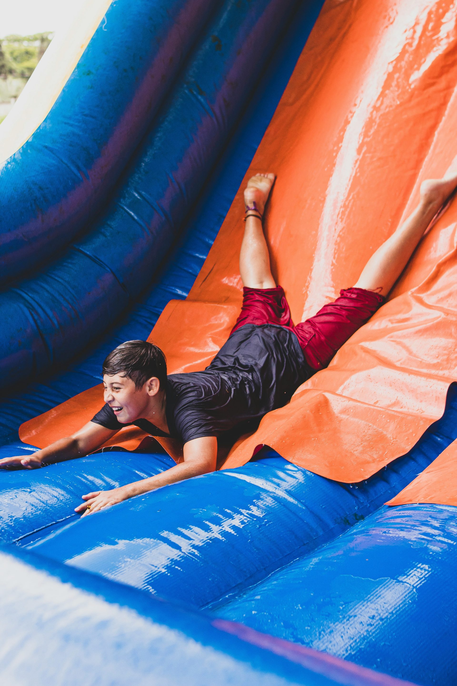 Ein junger Mann rutscht eine aufblasbare Rutsche hinunter.